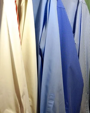 A close-up row of pressed dress shirts in blue, cream and white.