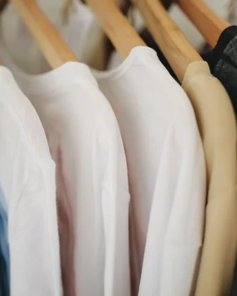Cream and white shirts hanging together on wooden hangers.