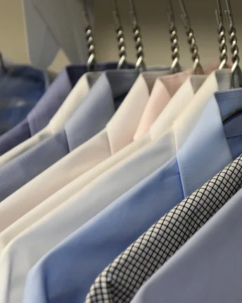 Suit jackets and dress shirts hanging side by side on a rail.