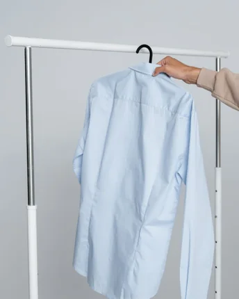 A crisp blue dress shirt hanging on a garment rail.