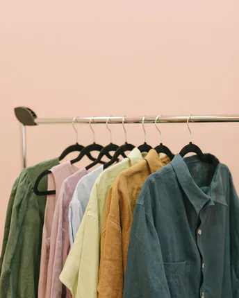 A rail of pressed linen shirts in green, pink and yellow.